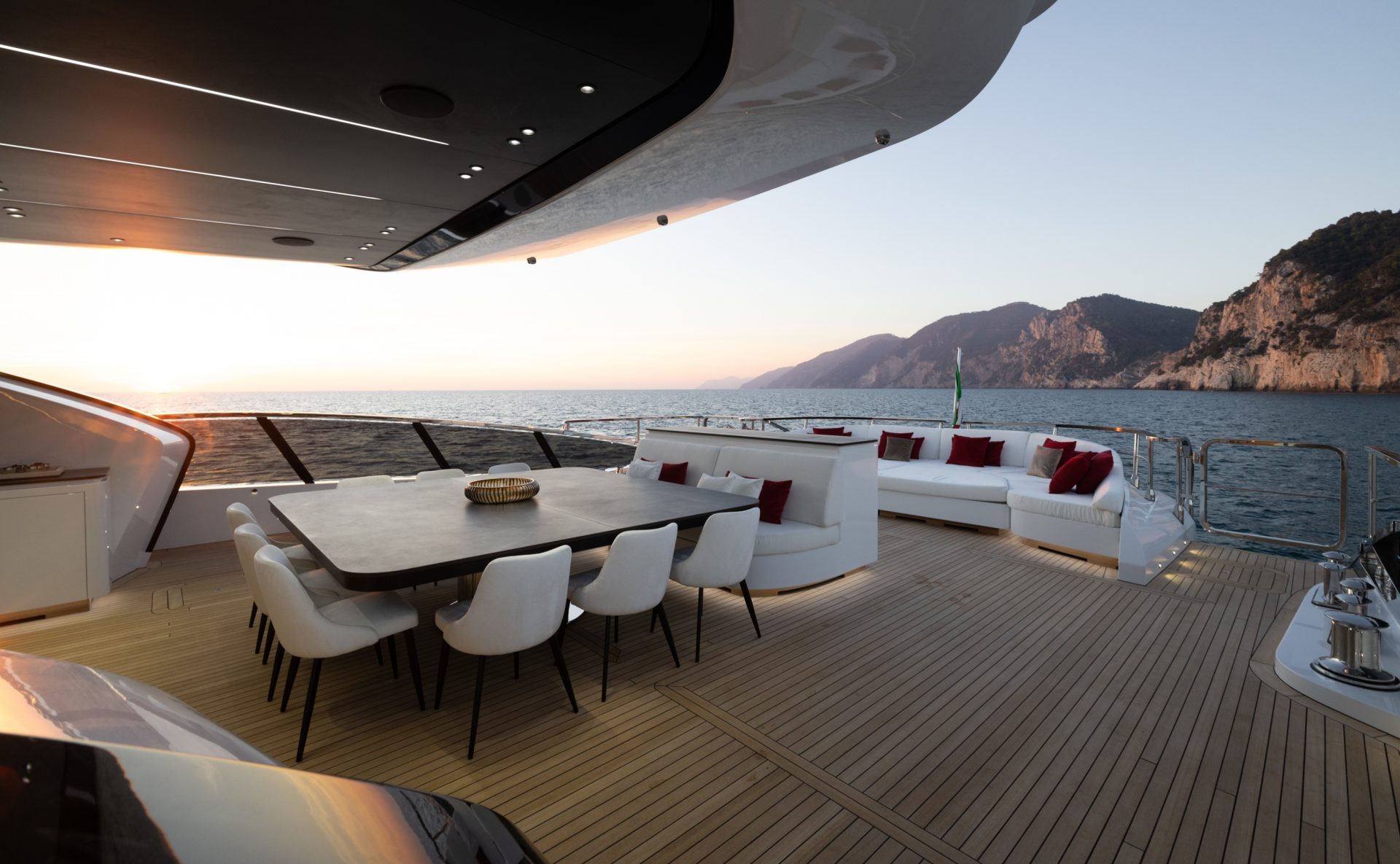 Luxury yacht deck with dining area at sunset.