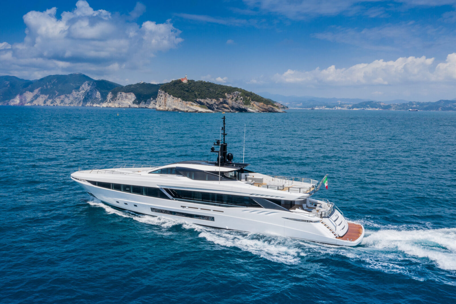 Yacht Mangusta naviga vicino a costa rocciosa.