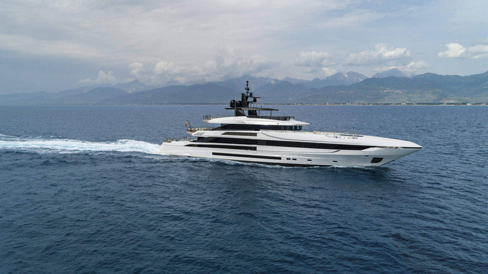 Mangusta yacht cruising on open sea with mountains in view.