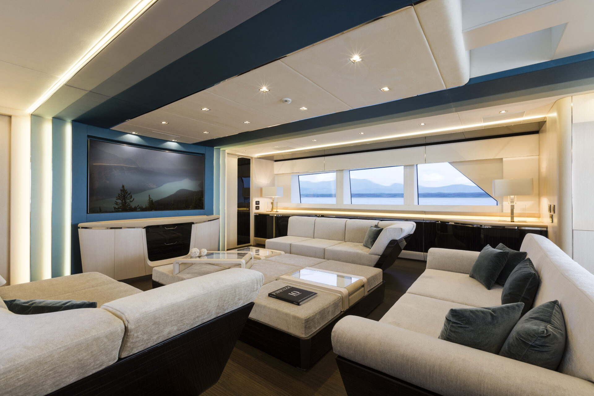 Luxury yacht interior with sofas and large windows.