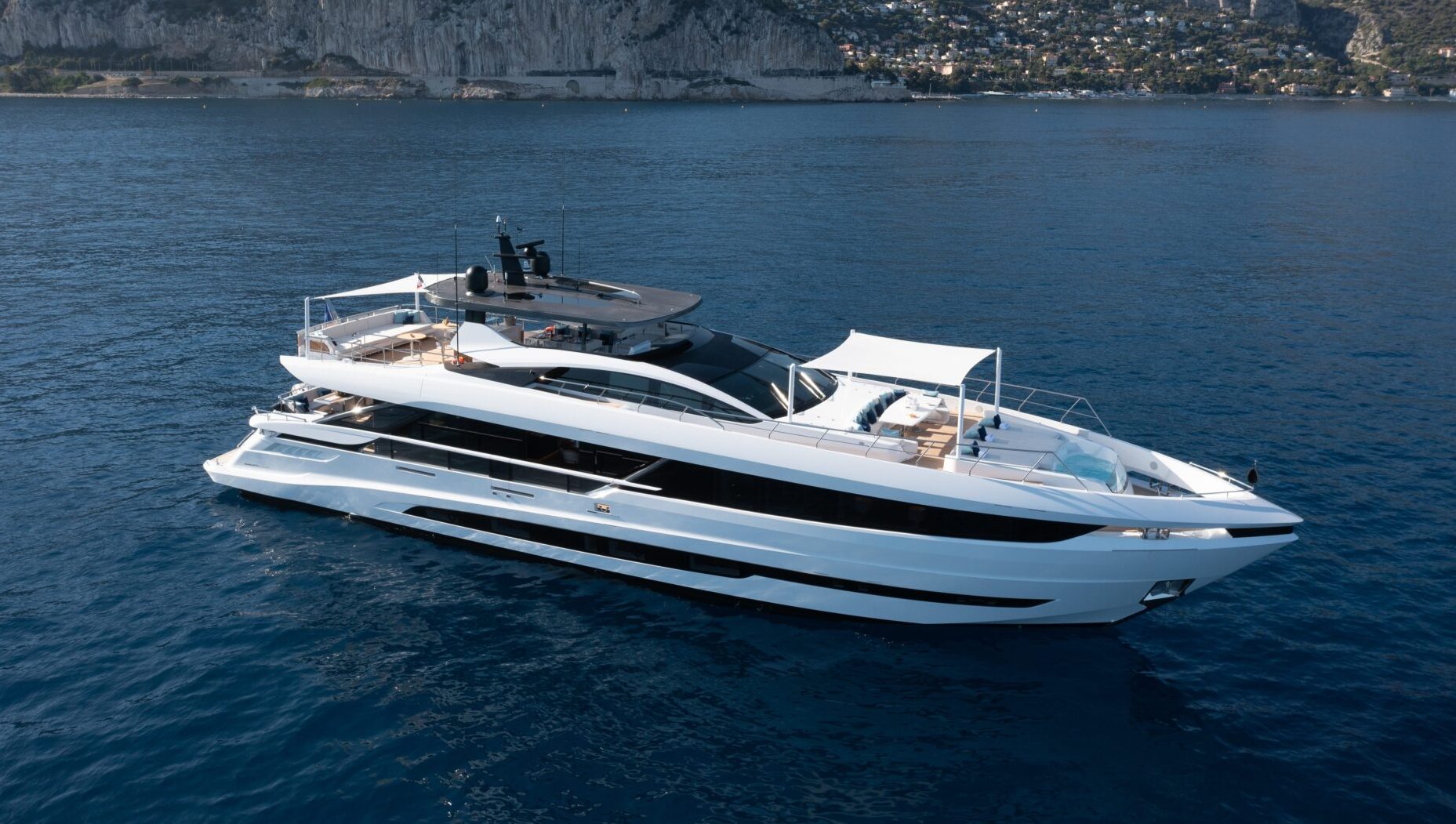 Yacht Mangusta in navigazione lungo la costa rocciosa.
