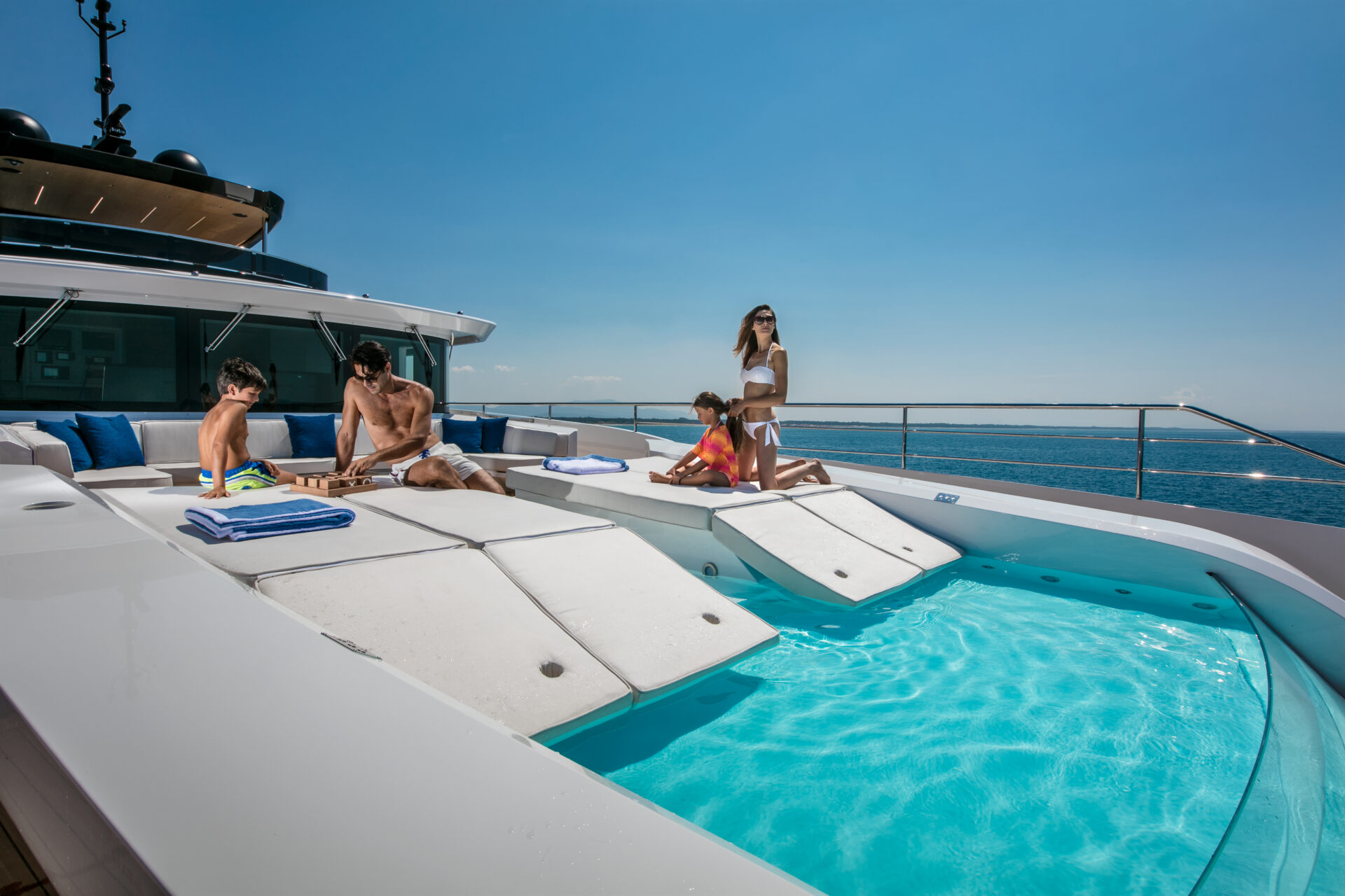 Family relaxing on Mangusta yacht sundeck by the pool
