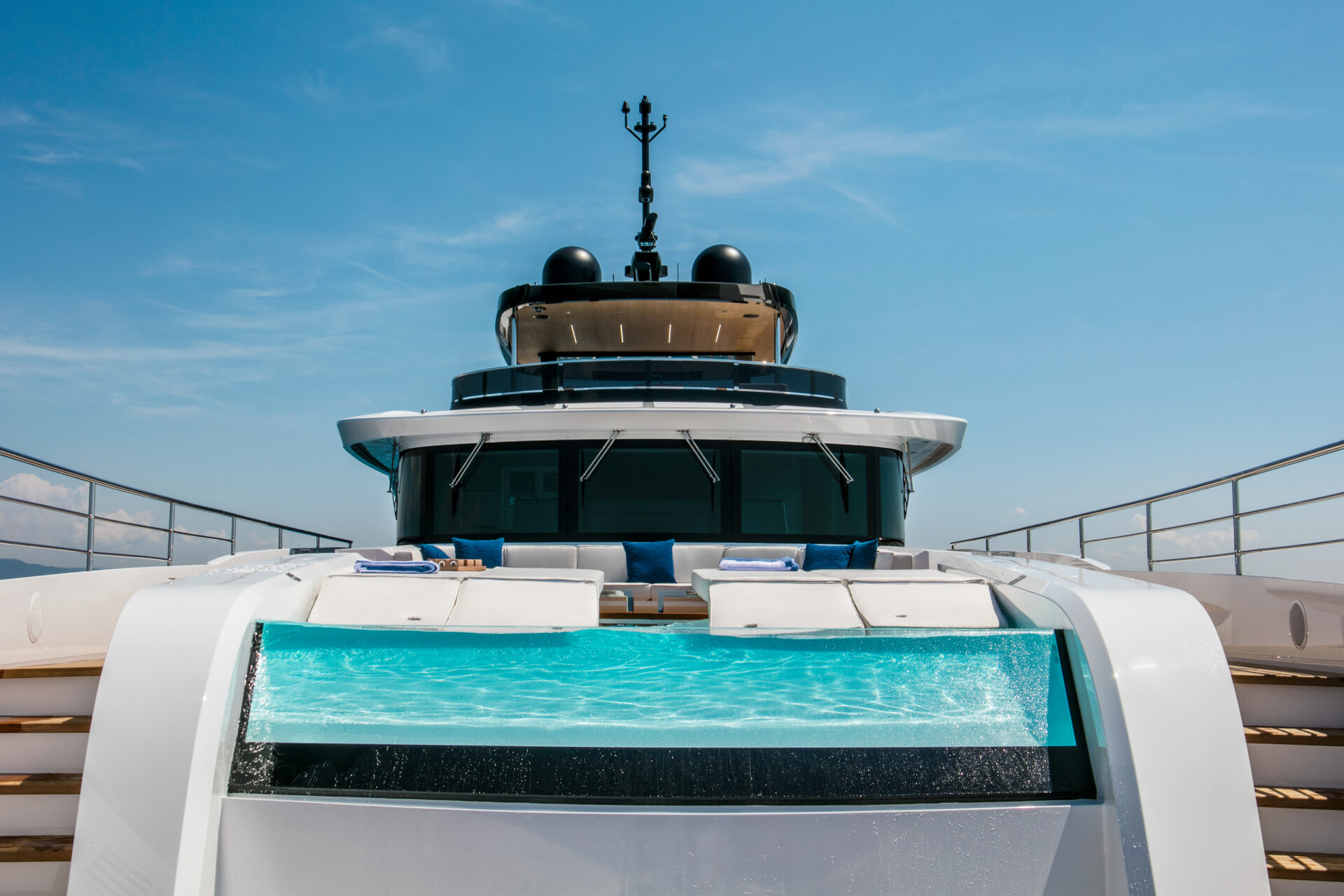 Luxurious pool on Mangusta yacht deck under blue sky.