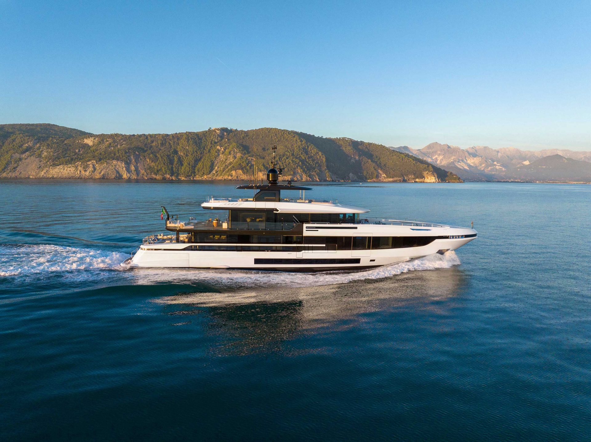 Luxury Mangusta yacht cruising by scenic coastline