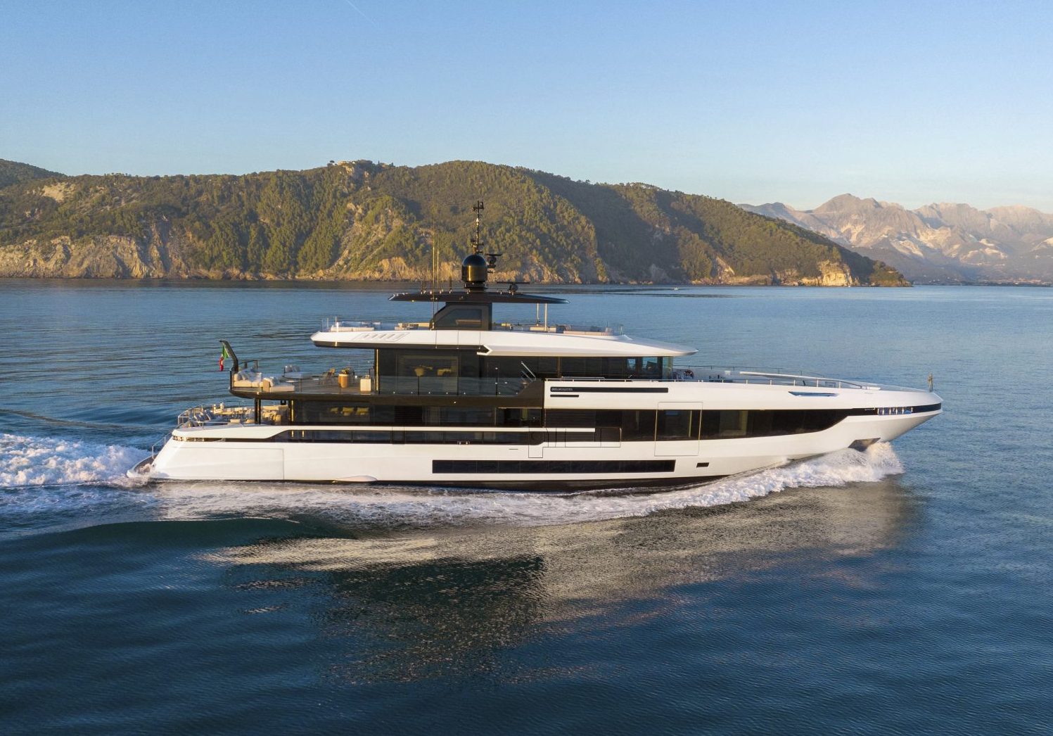 Yacht Mangusta naviga in panorama costiero.