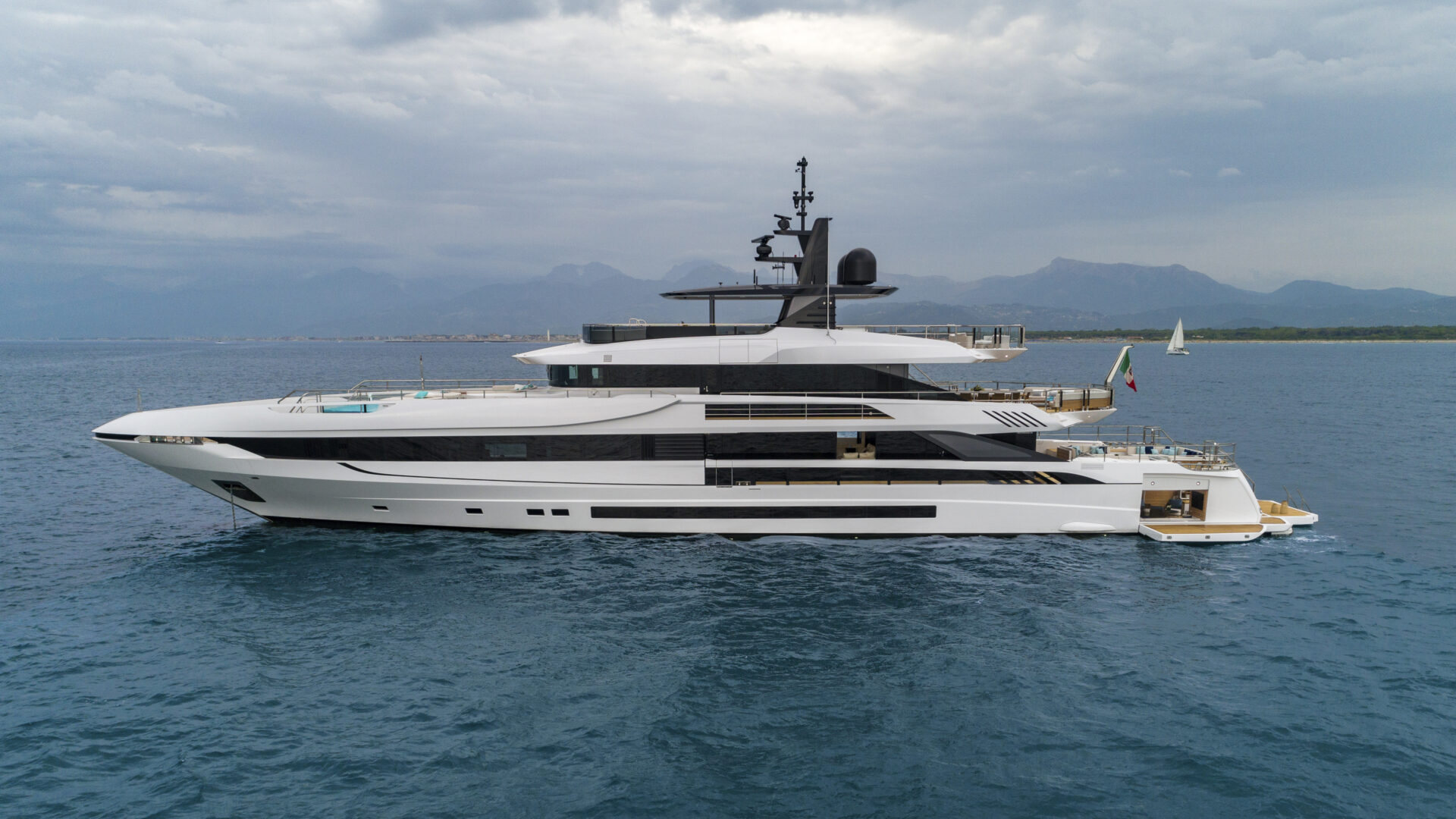 Mangusta Yacht cruising in open sea with mountains backdrop