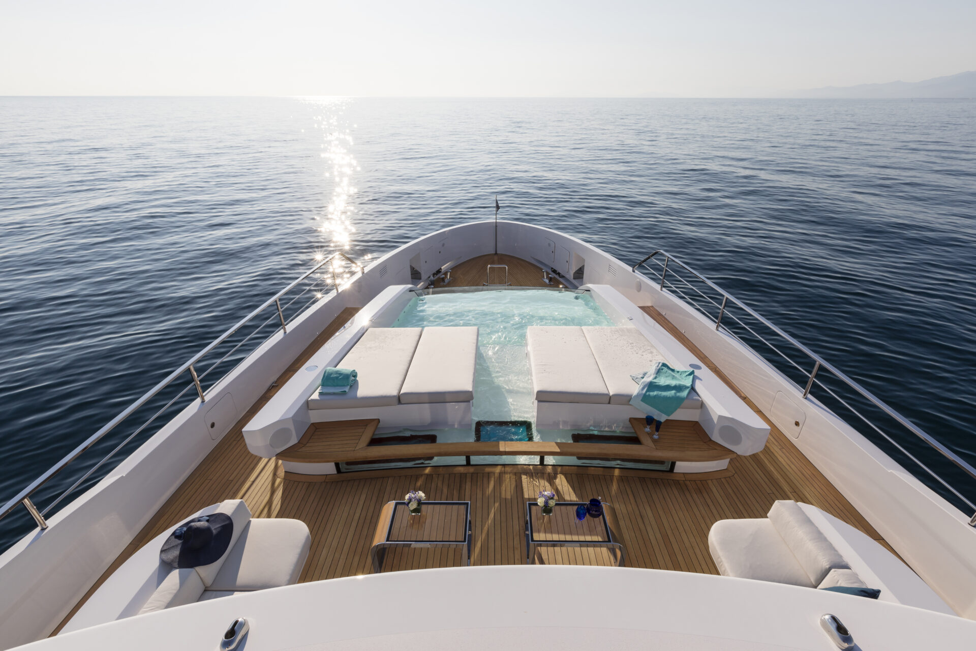 Luxury yacht bow with sun loungers and ocean view.