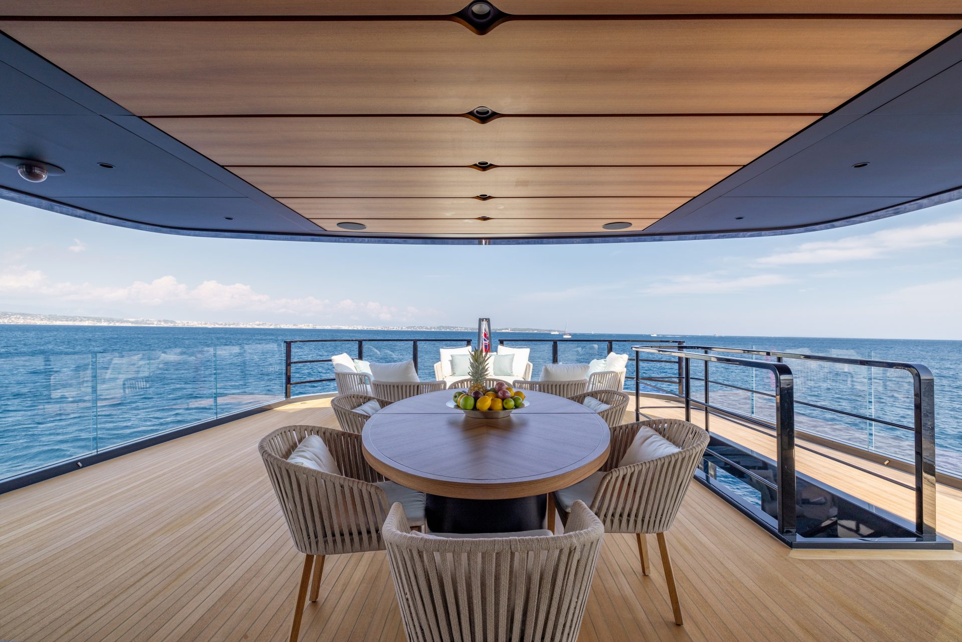 Yacht deck with dining table and ocean view.