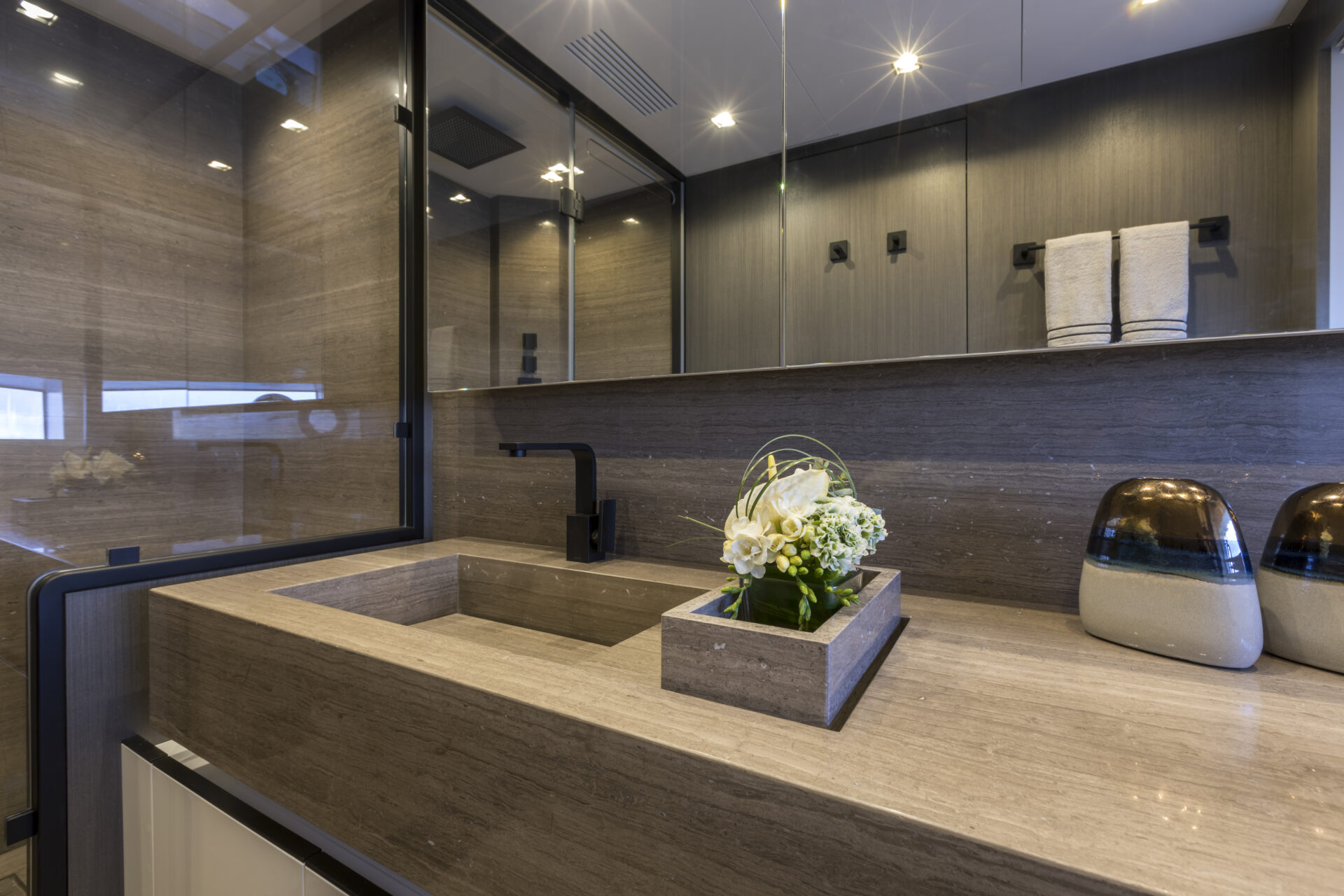 Luxurious yacht bathroom with stone sink and flowers.