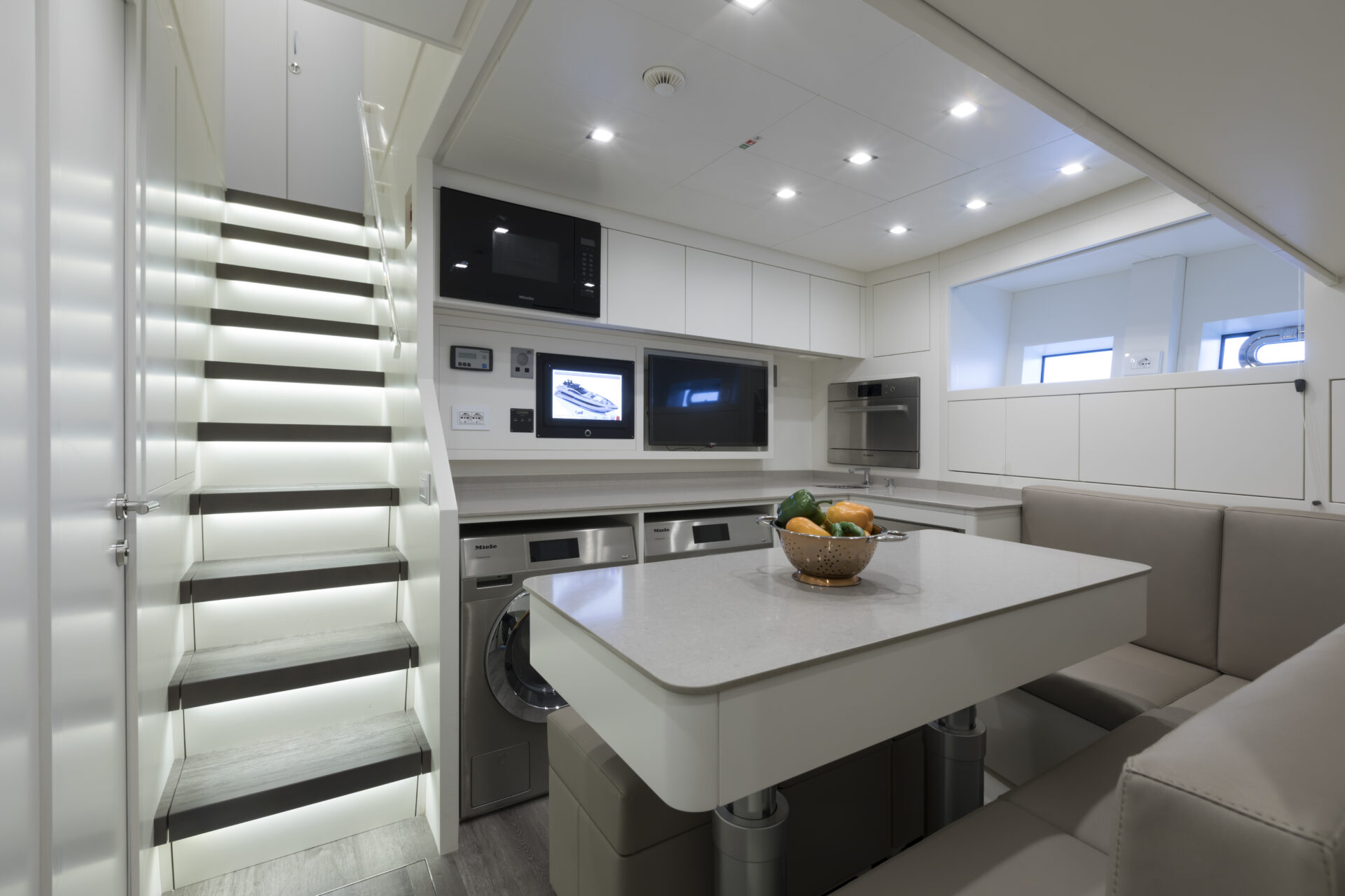 Modern yacht kitchen with stairs and seating area.