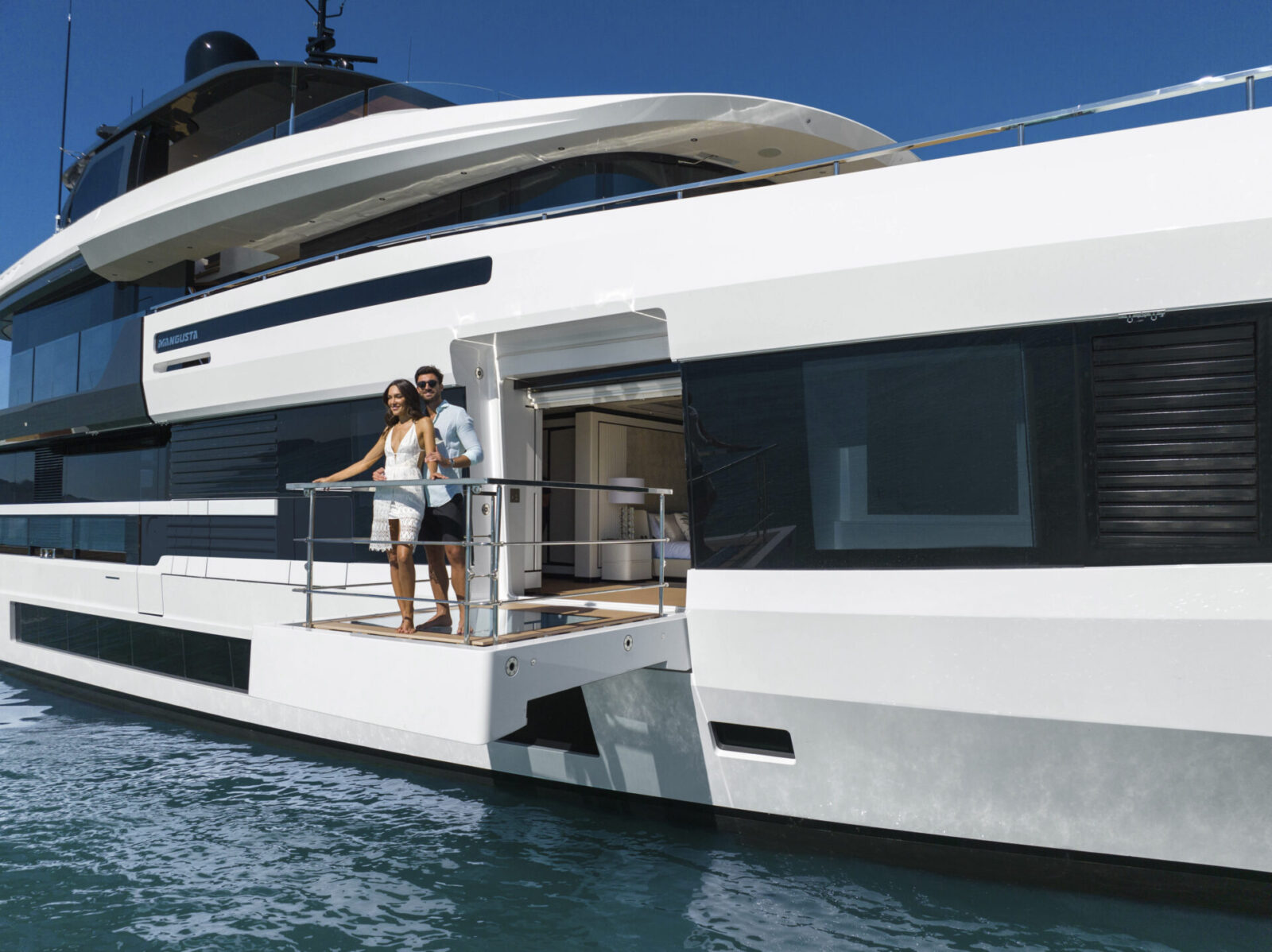 Coppia sul ponte di uno yacht Mangusta sotto il sole.