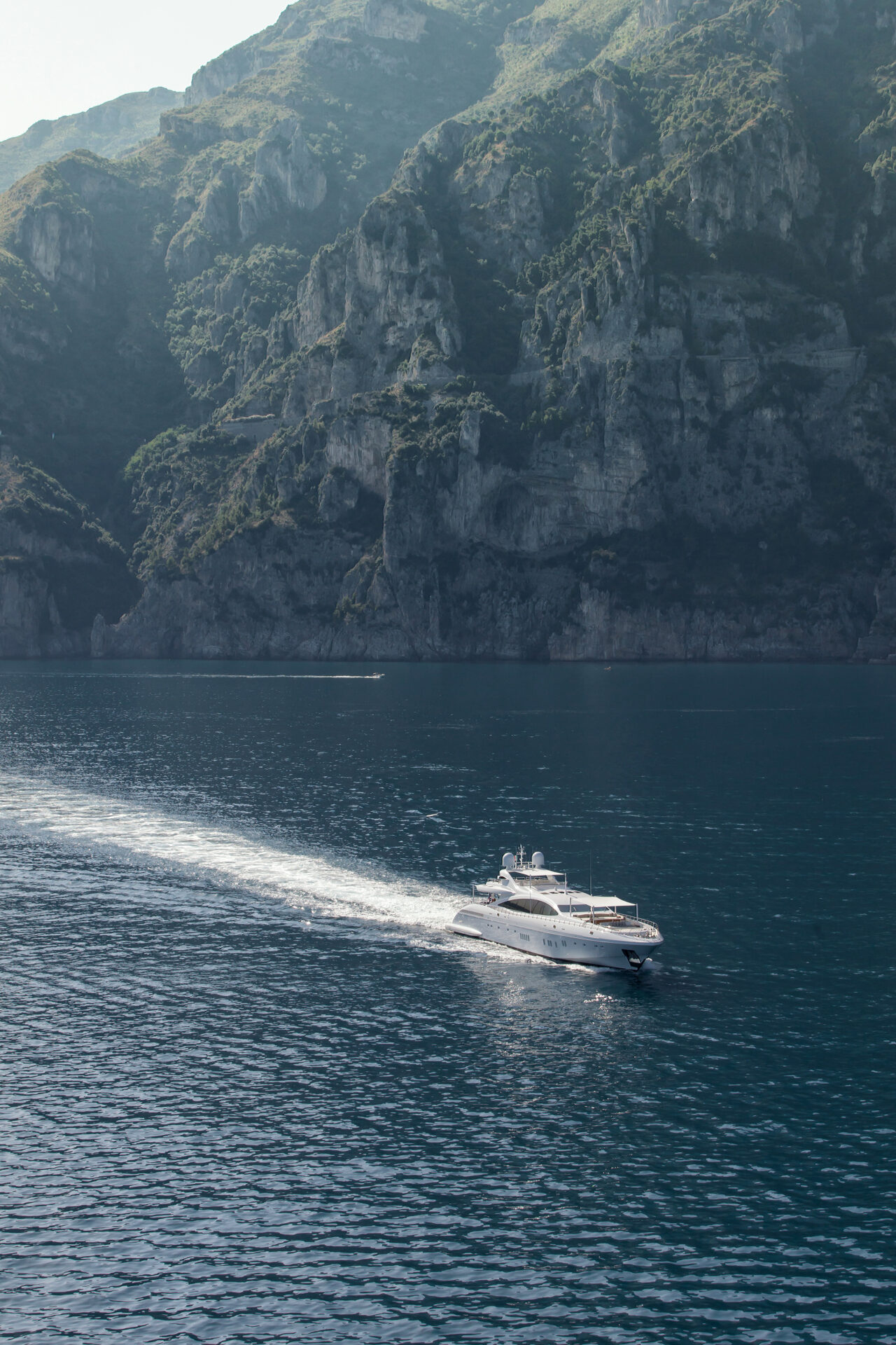 Yacht Mangusta naviga lungo la costa rocciosa.