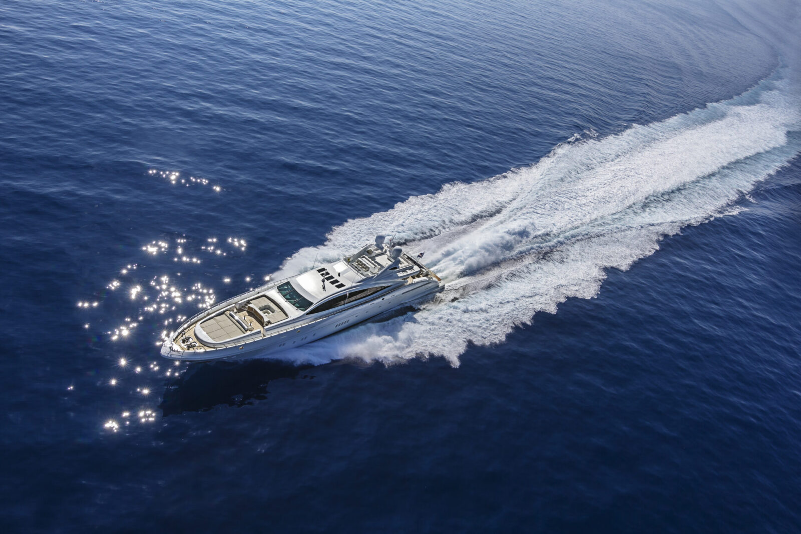 Yacht Mangusta sfreccia sull'acqua blu scintillante.