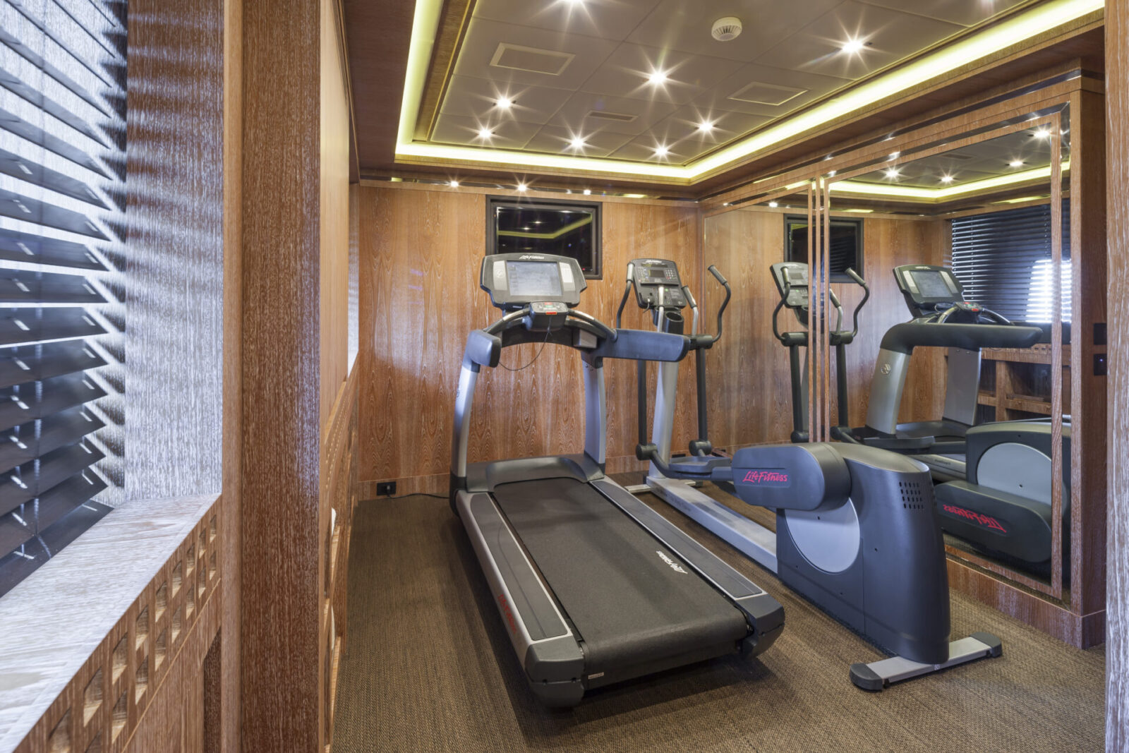 Yacht gym with treadmills and mirrored walls.