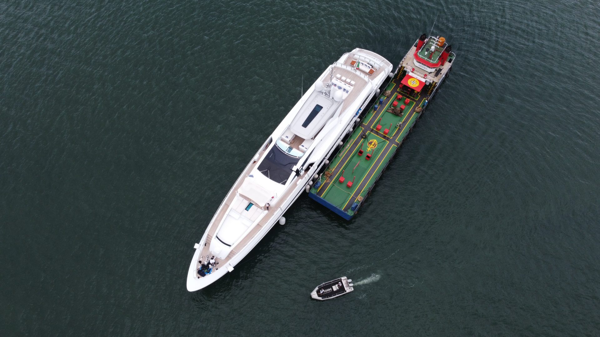 Yacht Mangusta attraccato accanto a una chiatta colorata.