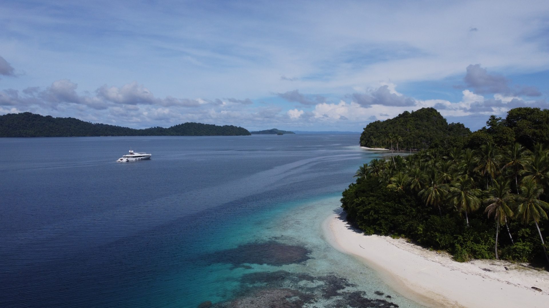 Yacht Mangusta al largo di isola tropicale lussureggiante.