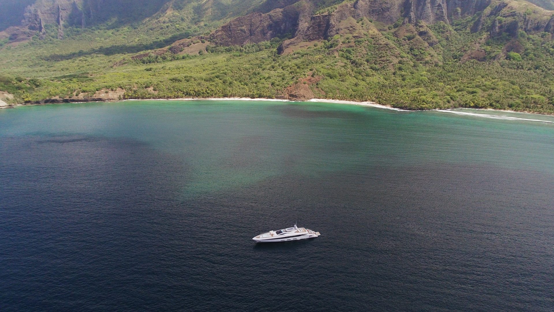 Yacht Mangusta in mare tropicale vicino a coste verdi.