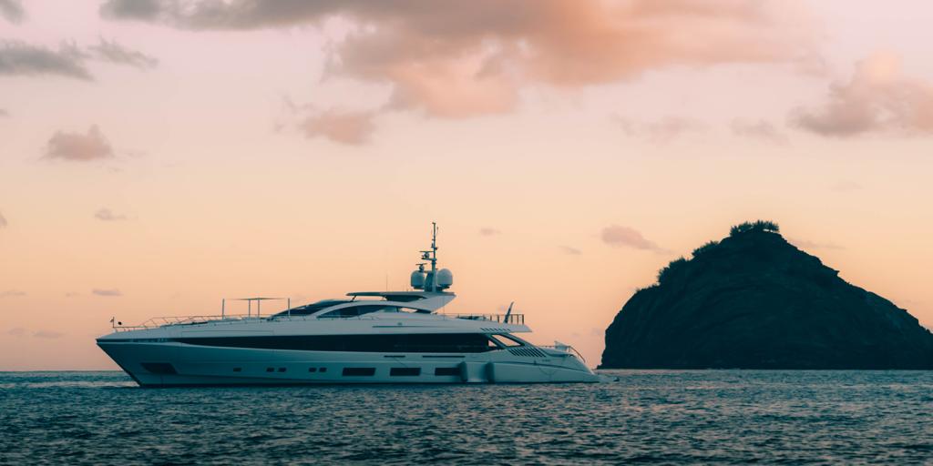 Yacht Mangusta al tramonto vicino a un'isola rocciosa.