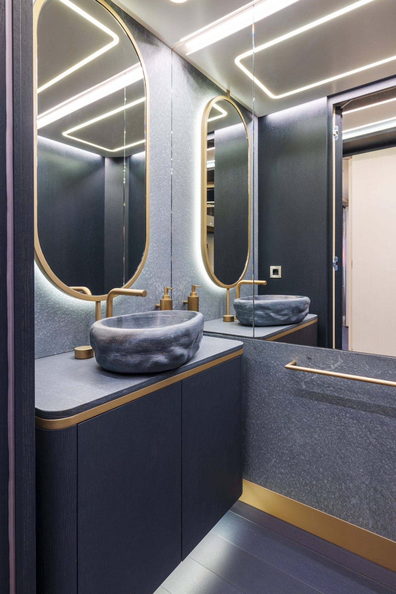 Bagno di lusso con lavabo in pietra e dettagli dorati.