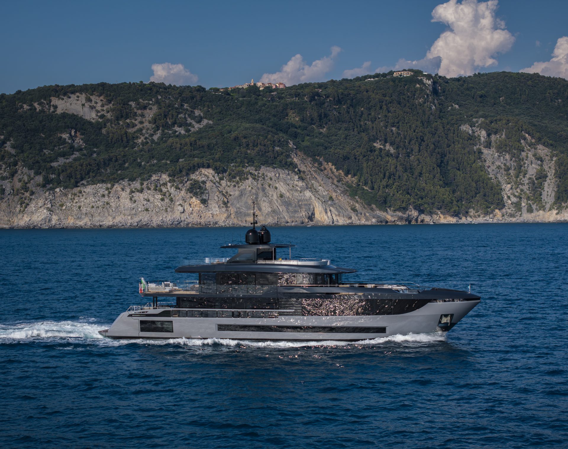 Mangusta yacht sailing near rocky coastline