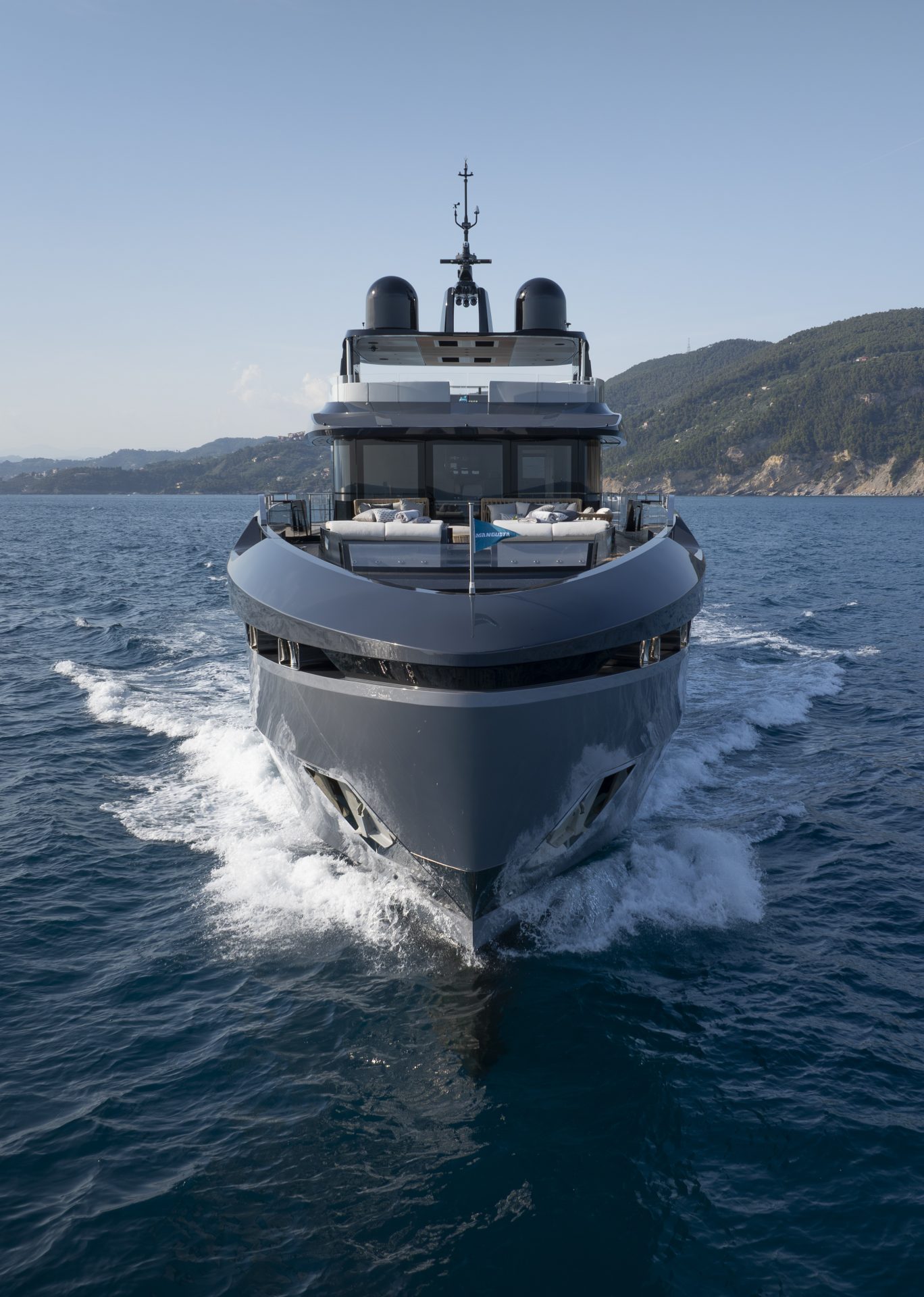 Yacht Mangusta solca il mare davanti a coste verdi.