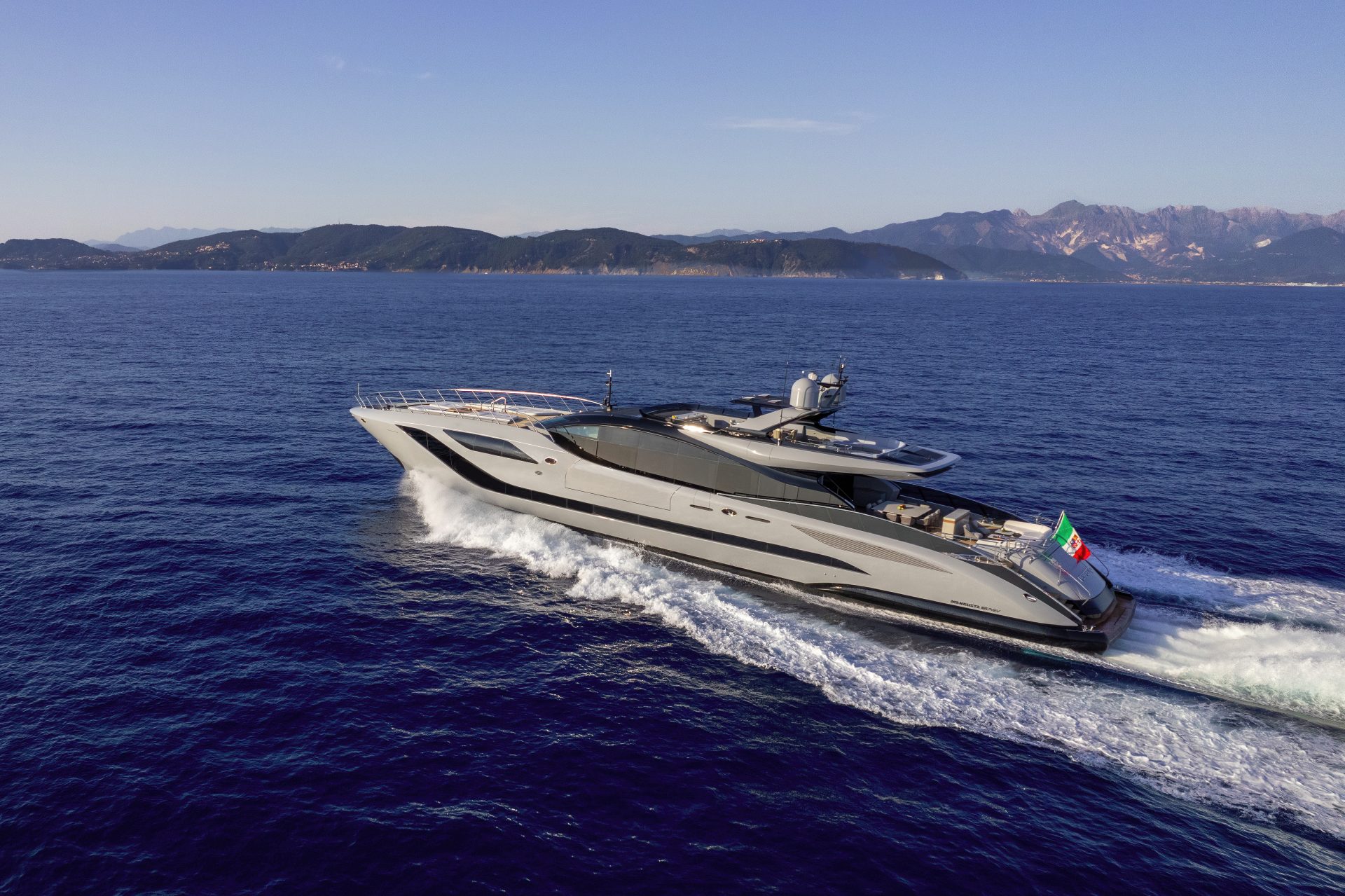 Mangusta yacht cruising on open sea, Italian flag visible.