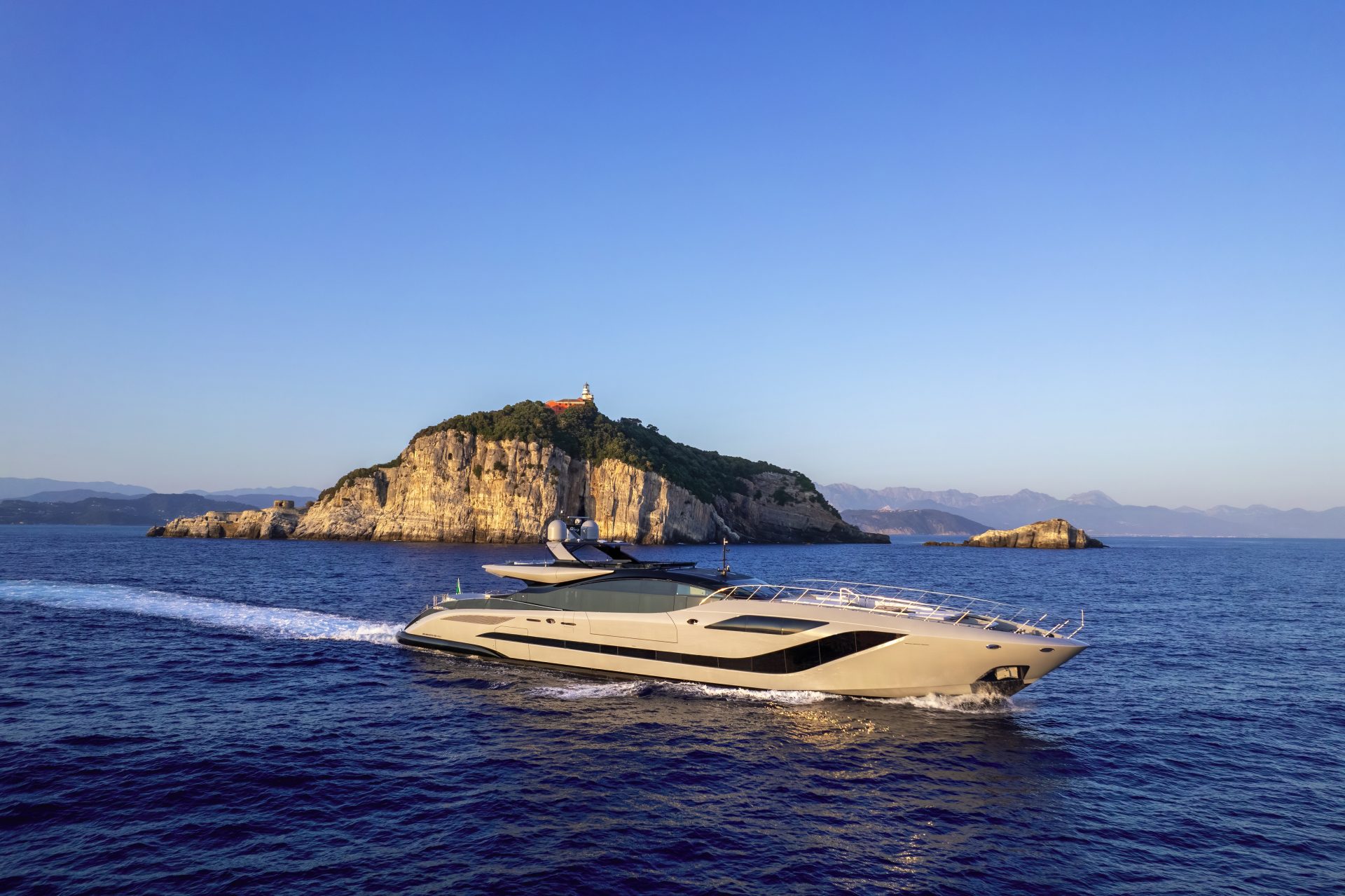 Mangusta Yacht cruising near rocky island coast