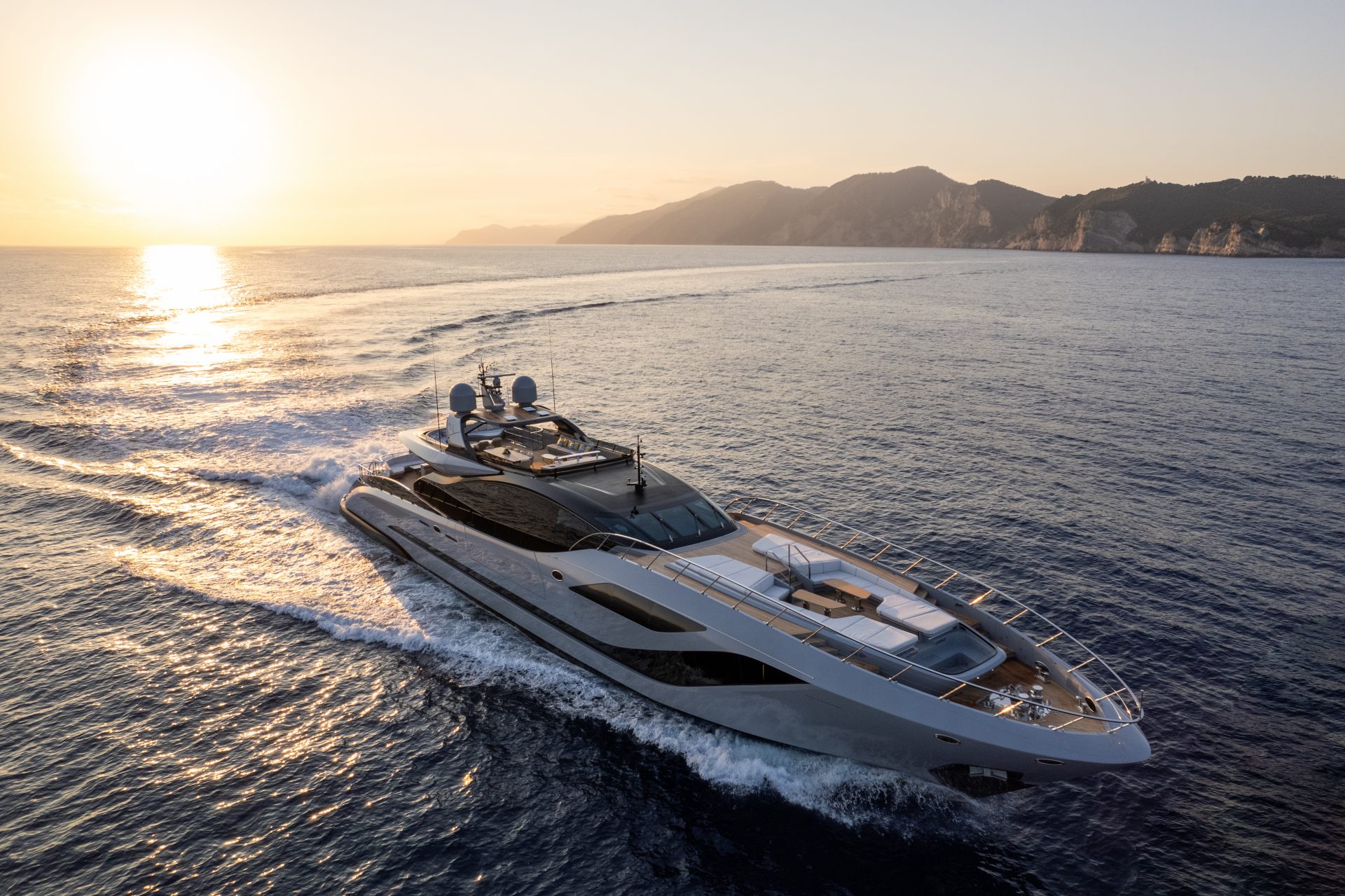Mangusta yacht cruising at sunset near coast