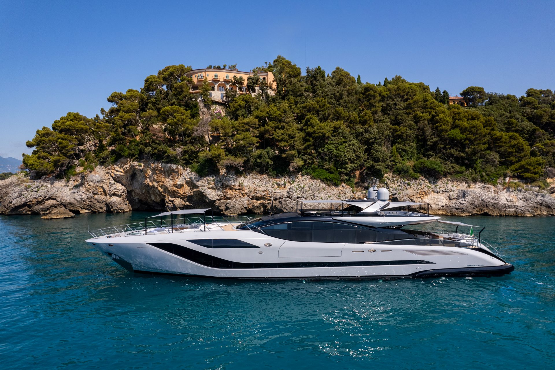 Luxurious Mangusta yacht near a scenic coastline.