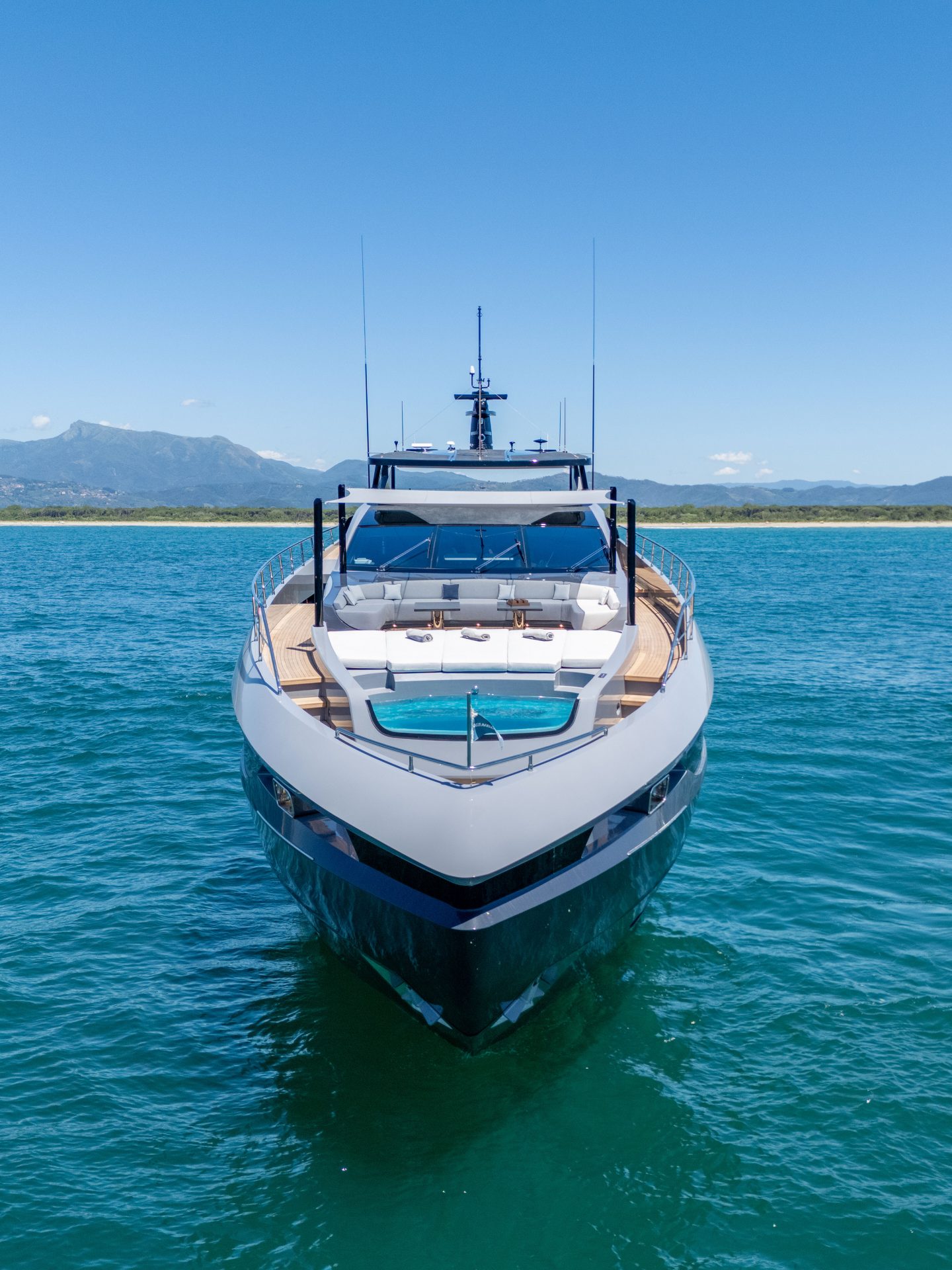 Yacht Mangusta su acqua azzurra con montagna sullo sfondo.