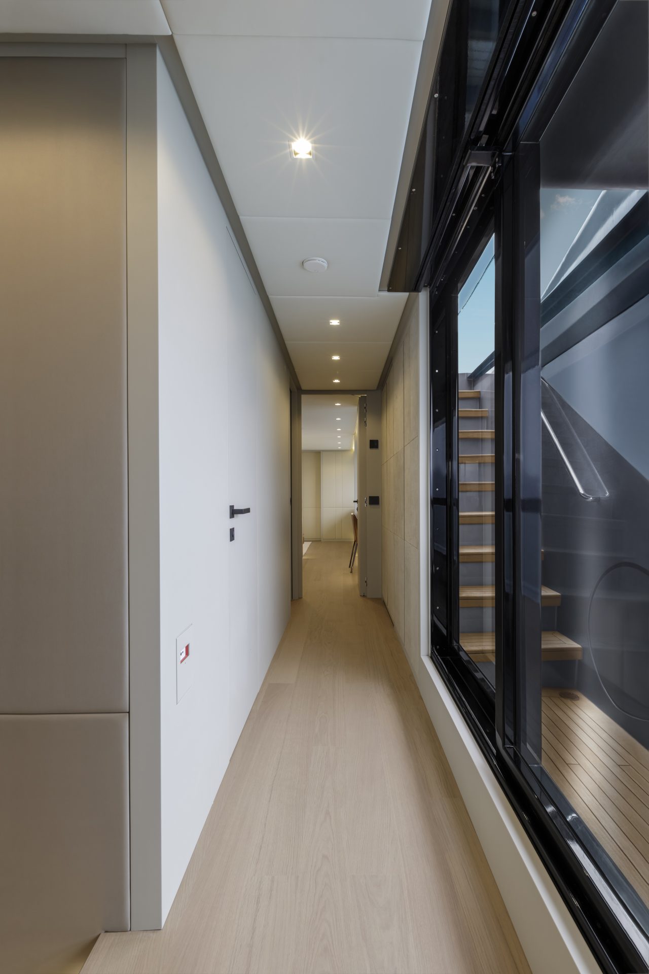 Sleek yacht corridor with stairs and modern lighting.