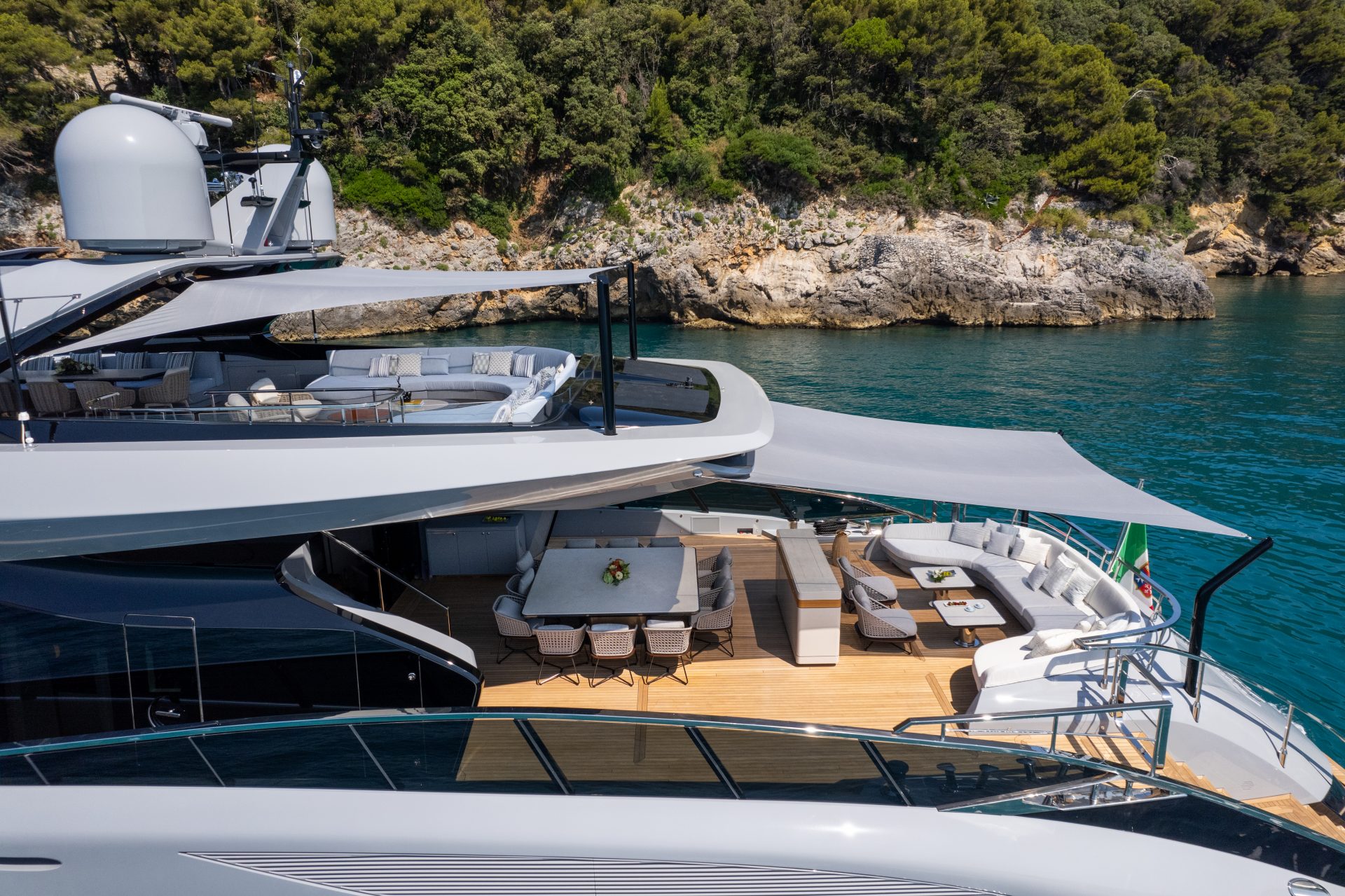 Luxurious deck view on Mangusta Yacht by a rocky shore.