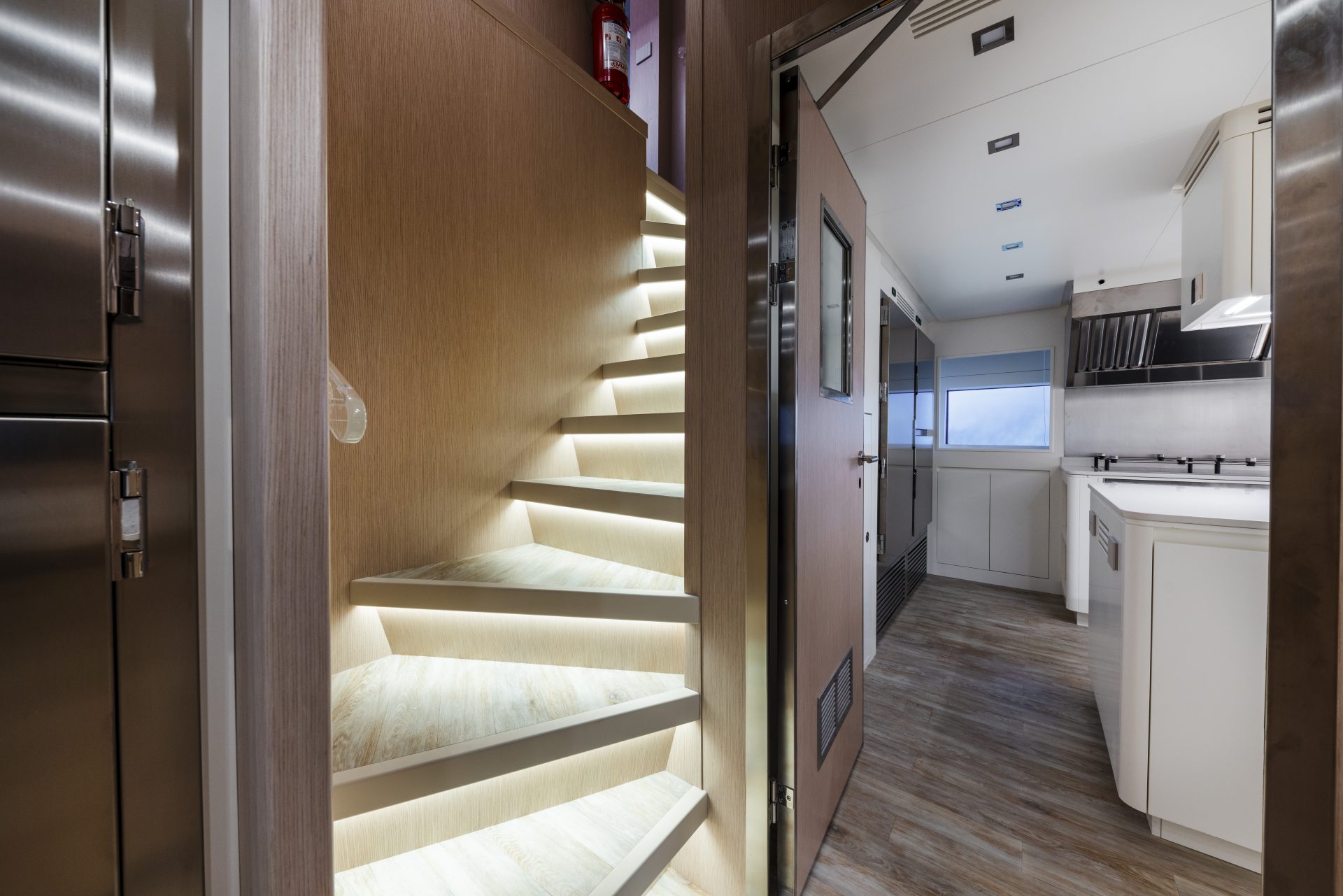 Modern yacht interior with wood stairs and kitchen.