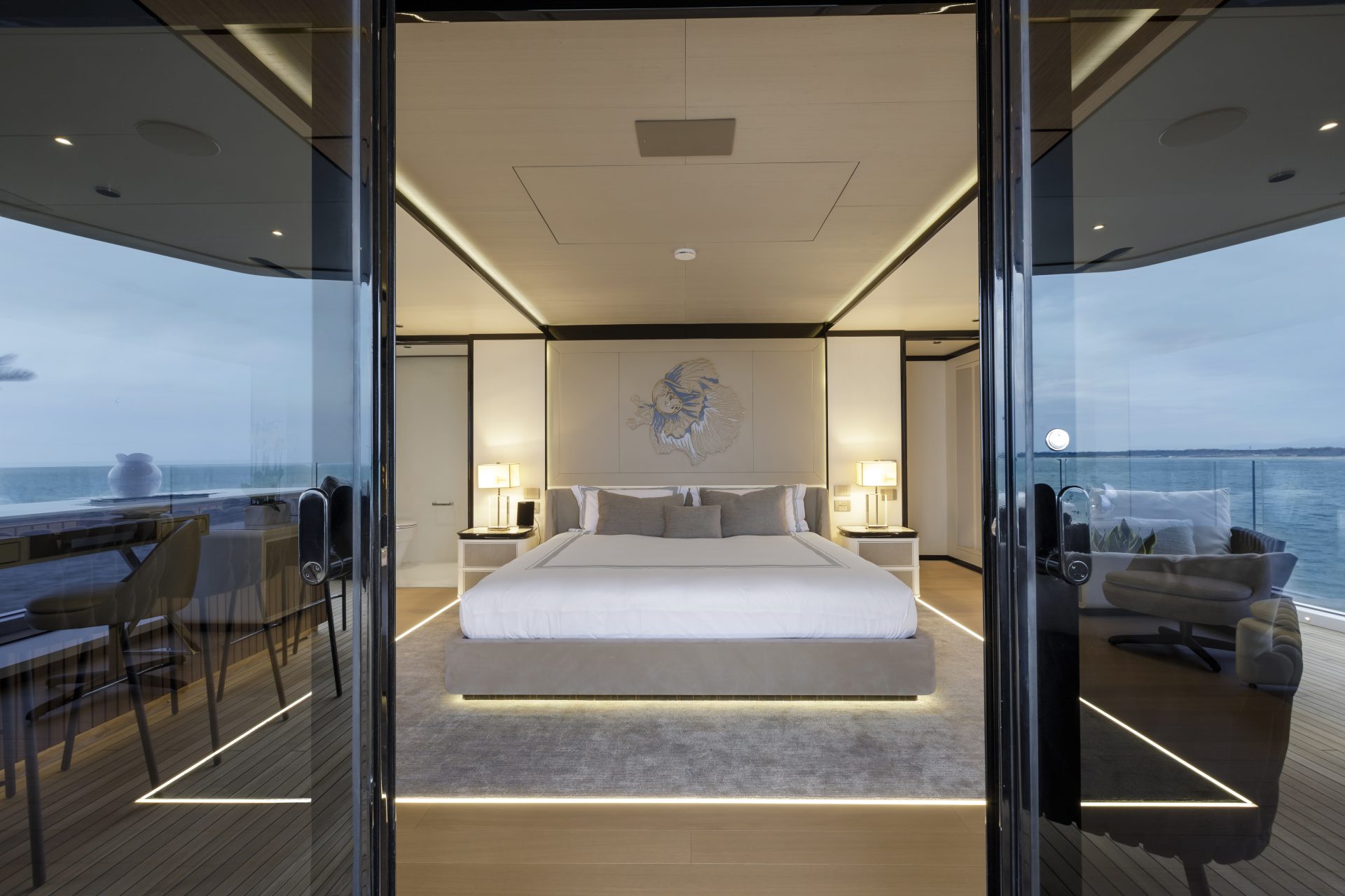 Suite di lusso su yacht Mangusta, letto king-size, illuminazione moderna, vista sull'oceano, dettagli eleganti e arredo contemporaneo.