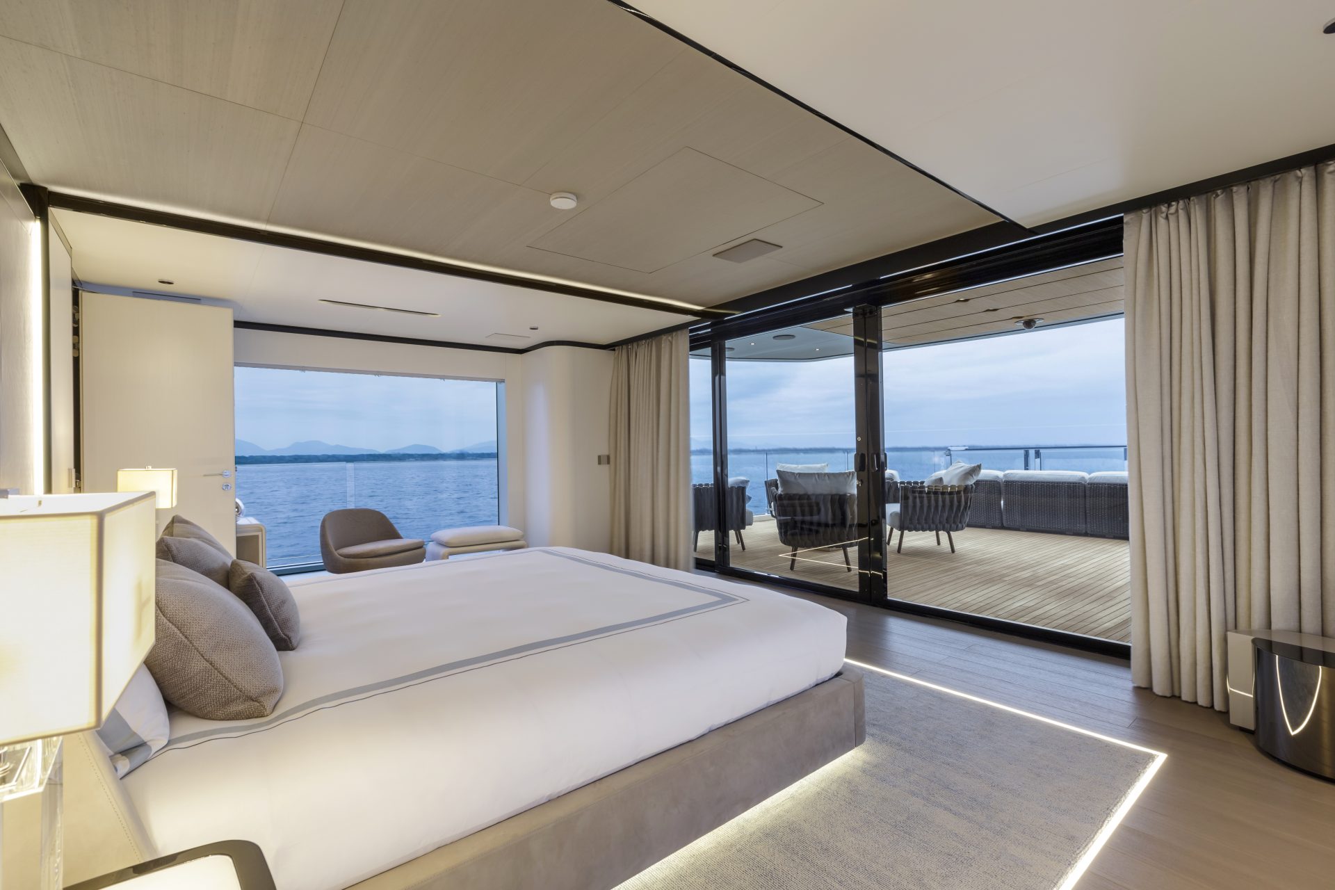 Camera da letto di lusso su uno yacht Mangusta, con vista sul mare, arredi moderni e ampia terrazza esterna.