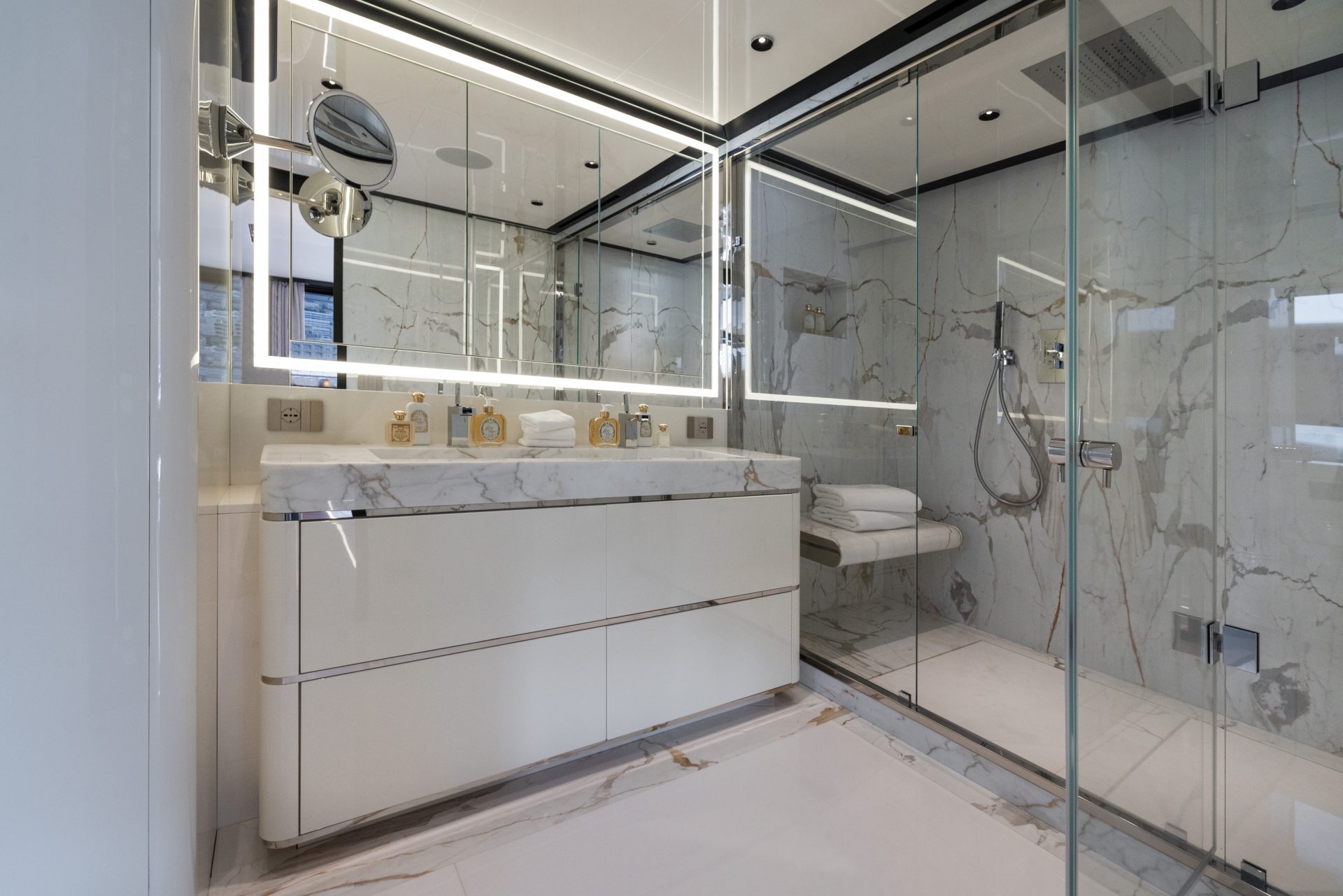 Bagno elegante in marmo su uno yacht di lusso Mangusta, con lavandino moderno e doccia a pioggia in vetro. Ambiente raffinato e contemporaneo.