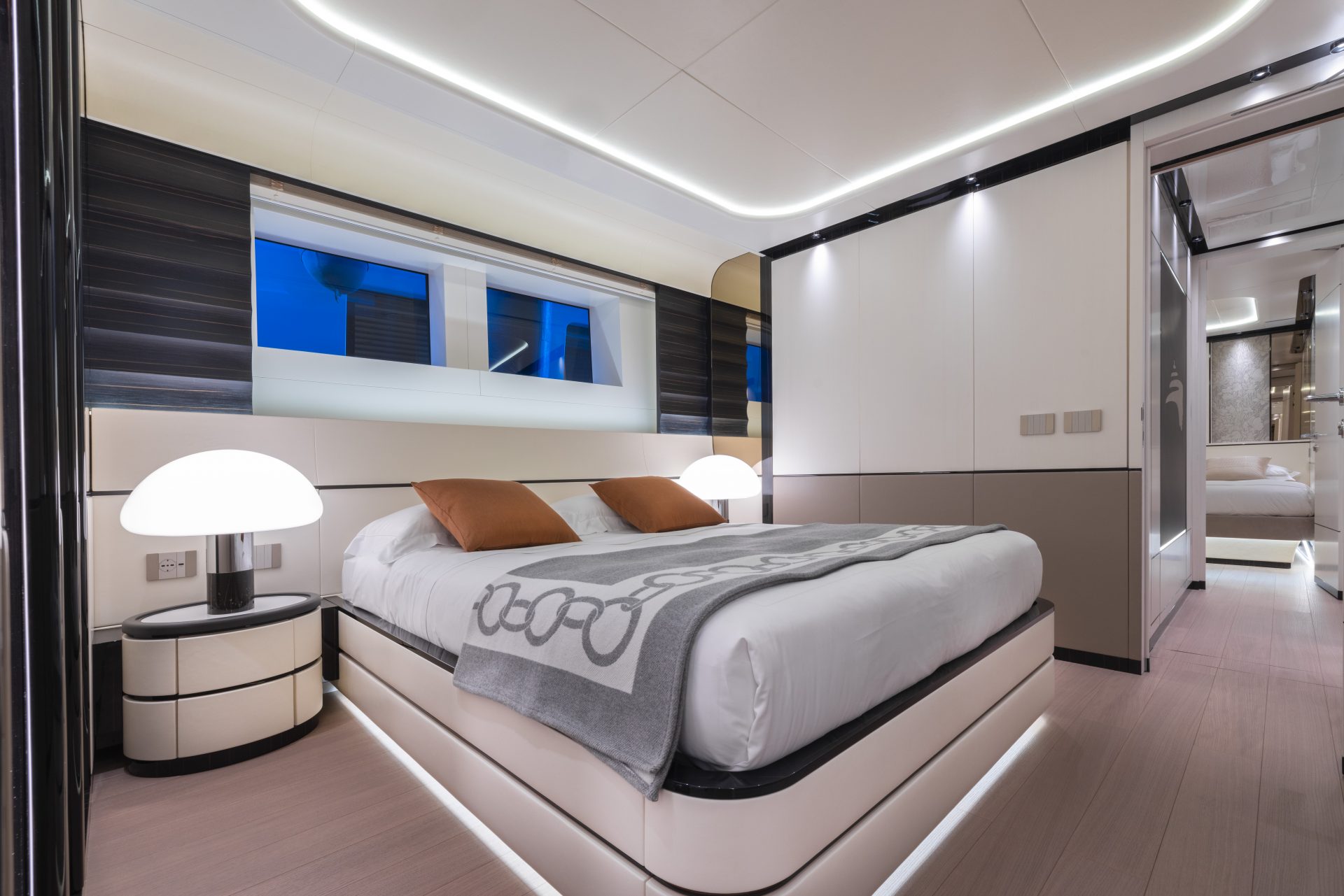 Cabina elegante di uno yacht Mangusta, arredi moderni con letto matrimoniale, lampade di design e illuminazione soffusa.