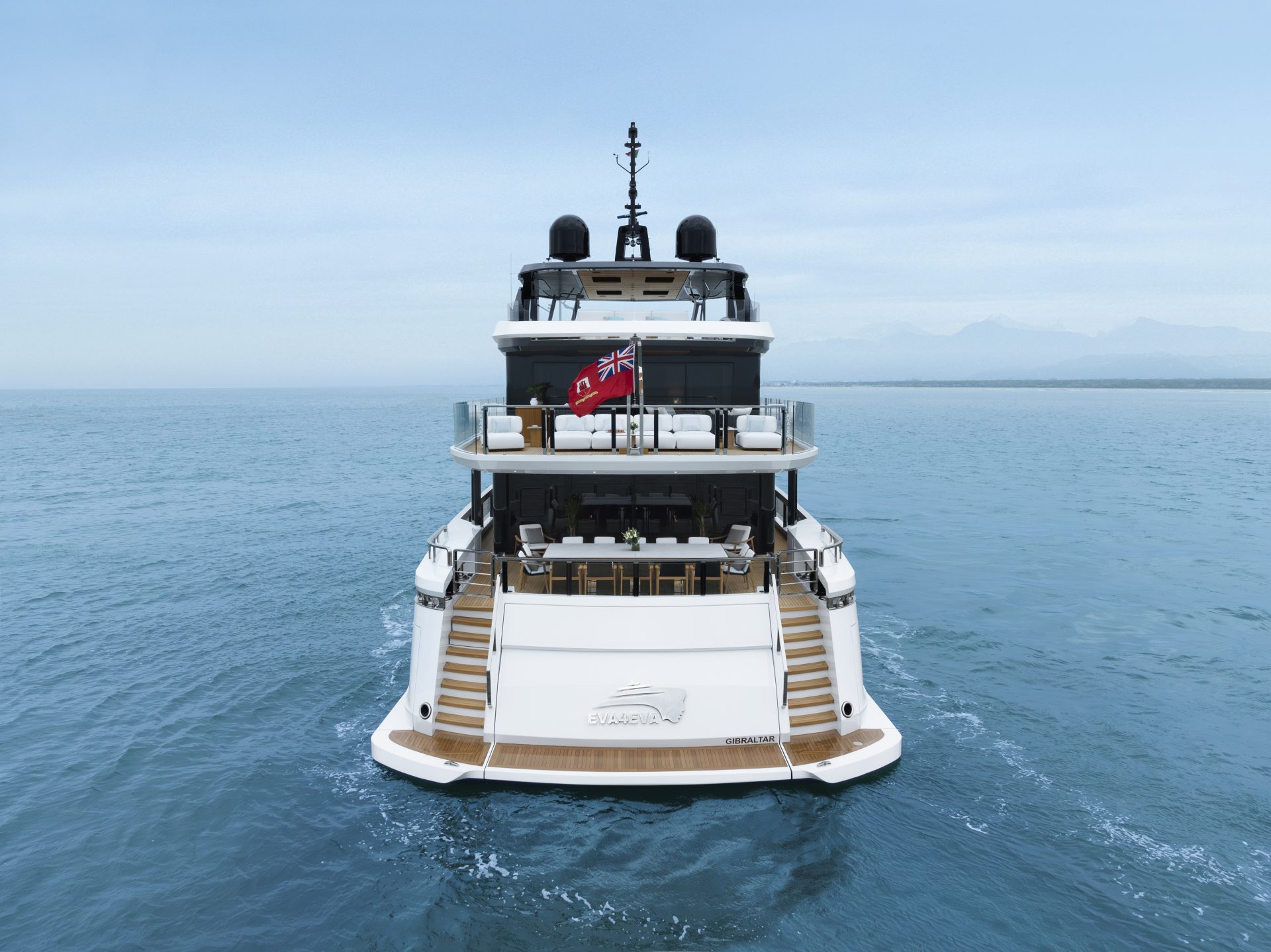 Yacht Mangusta sul mare azzurro con bandiera rossa.
